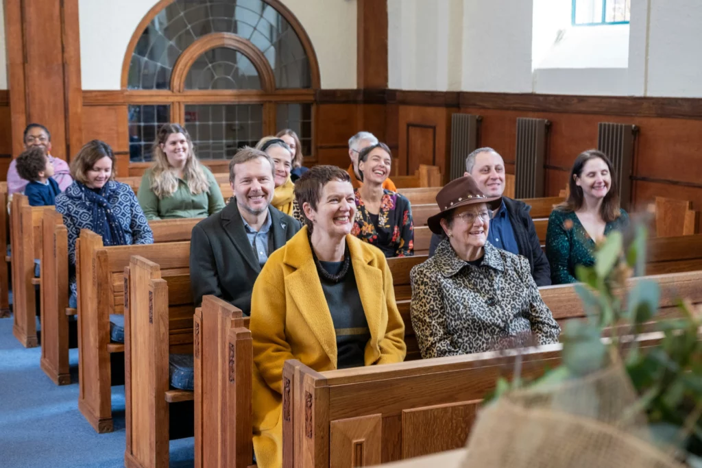 Assistance souriante et recueillie lors d'une cérémonie de mémoire dans une église.